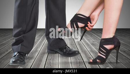 Digital composite of Businessman's feet and woman's high heels on wooden floor Stock Photo