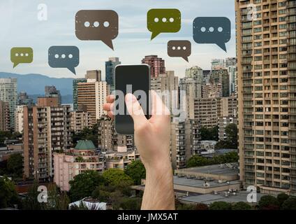Digital composite of Holding phone and Chat bubble icons over city Stock Photo