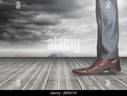 Digital composite of Mans leg and foot on wood with dark clouds Stock Photo