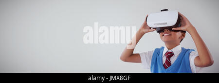 Schoolboy using virtual reality headset against white background Stock Photo