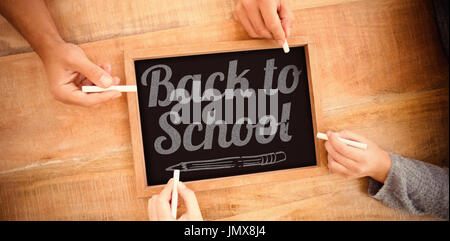 Back to school text over white background against hands writing on chalkboard Stock Photo