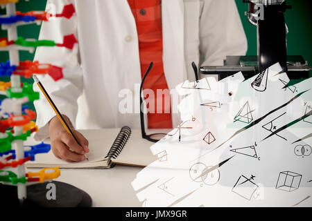 Various geometric shapes on black scribbling against schoolboy writing on book against green background Stock Photo