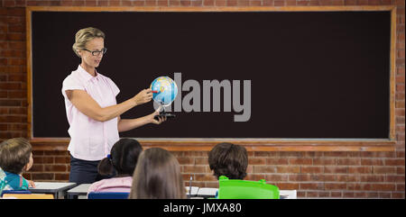 Teacher with students holding globe against large chalkboard in classroom Stock Photo