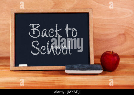 Back to school text on white background against blackboard with duster and apple Stock Photo
