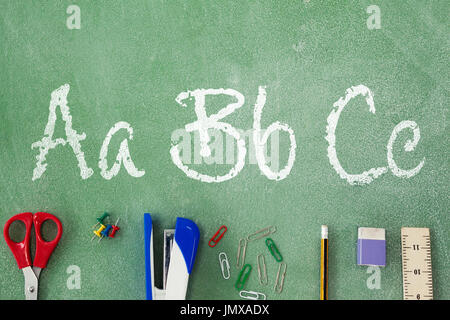 Letters on white background against overhead view of stapler with pencil on table Stock Photo