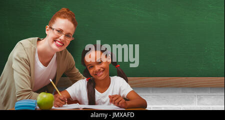 Happy pupil and teacher against greenboard on wall in school Stock Photo