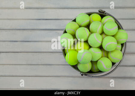 Overhead view of tennis balls in metallic bucket on white wooden table Stock Photo