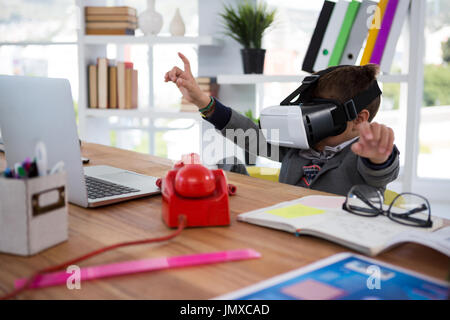 Boy as business executive using virtual reality headset in office Stock Photo