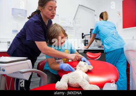 Child at dentist's Editorial use only   MODEL RELEASED. Child at dentist's with teddy bear and dental nurses. Stock Photo