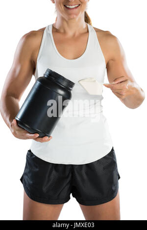 Mid section of smiling female athlete taking supplement powder while standing against white background Stock Photo