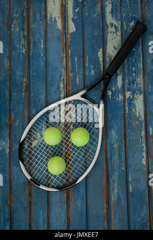 Overhead view of tennis racket and balls on blue wooden table Stock Photo