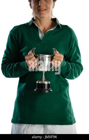 Mid section of smiling female rugby player holding trophy while standing against white background Stock Photo