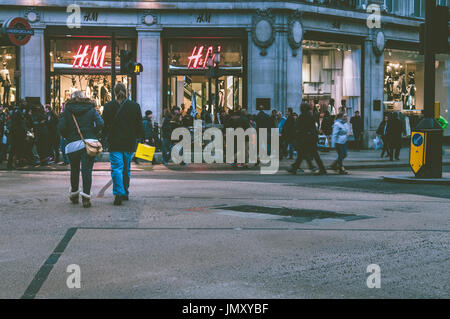 Shoppers walk past H&M shop located on Oxford street, London. Stock Photo