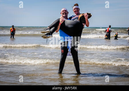 Log carry into the sea, unusual obstacle on obstacle course race. Stock Photo