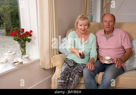 Couple sitting on a sofa using a remote TV controller Stock Photo