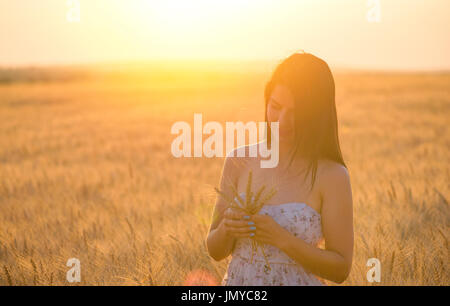 beautiful woman with a wheat bouguet in wheat field at sunset Stock Photo