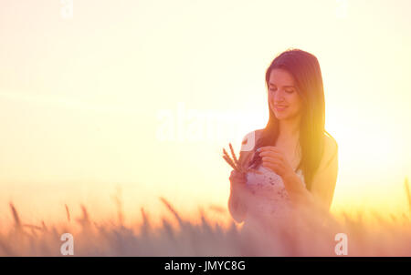 beautiful woman with a wheat bouguet in wheat field at sunset Stock Photo