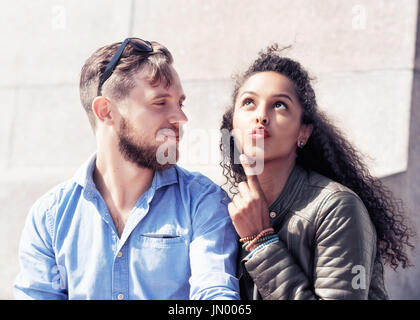 Young middle eastern girl asking for kiss from her caucasian boyfriend as diversity friendship and togetherness concept Stock Photo