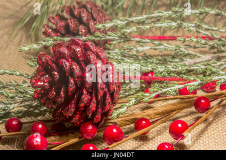 Christmas Decorations with Pine Cones and Berries on a Hessian background. Stock Photo