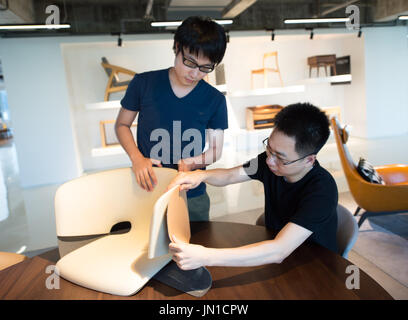 (170729) -- HANGZHOU, July 29, 2017 (Xinhua) -- Zhao Lei (R) and Zhang Jingxiang discuss the design of a chair in the headquarters of MZGF in Hangzhou, east China's Zhejiang Province, July 28, 2017. Zhao Lei established MZGF in 2010 and dedicated to design a wide range of furniture suitable for contemporary life. China's furniture industry is embracing a new wave of independent designer brands, especially in cities like Beijing, Shanghai and Hangzhou. The new generation of designers attaches more importance on the contemporary expression of Chinese elements, adding creative momentum to the fur Stock Photo