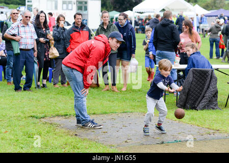 Boy bowling a ball at skittles at a country fair, Damerham, Fordingbridge, Hampshire, UK Stock Photo