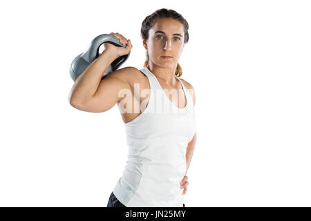 Portrait of female athlete holding kettlebell while standing against white background Stock Photo