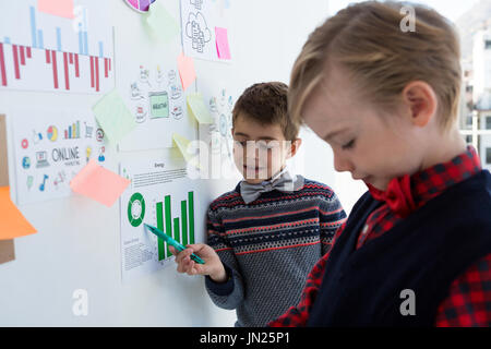 Kids as business executives discussing over whiteboard in office Stock Photo