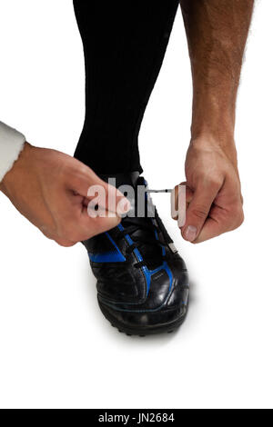 Cropped image of sports player tying shoelace against white background Stock Photo