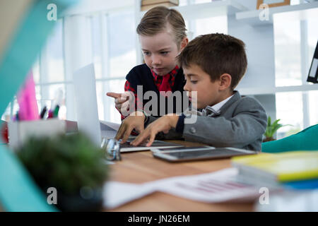 Kids as business executives discussing over laptop in office Stock Photo