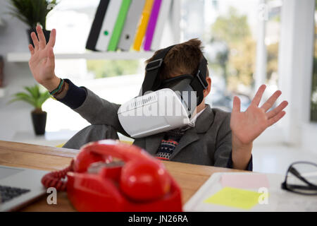 Boy as business executive using virtual reality headset in office Stock Photo