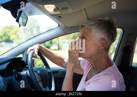 Active senior woman looking into rear view mirror while driving a car Stock Photo