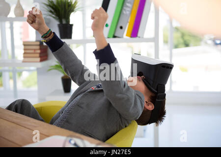 Boy as business executive using virtual reality headset in office Stock Photo