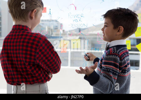 Kids as business executives discussing over whiteboard in office Stock Photo