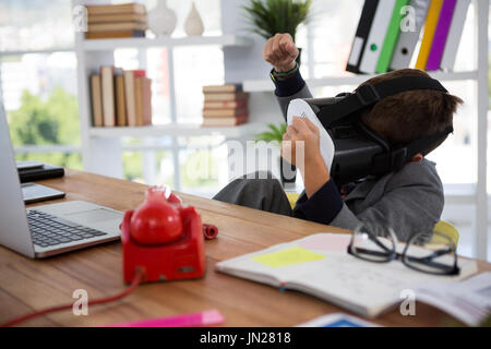 Boy as business executive using virtual reality headset in office Stock Photo