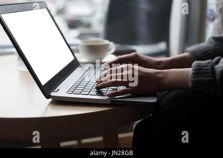 Cropped image of woman using laptop at table in cafe Stock Photo