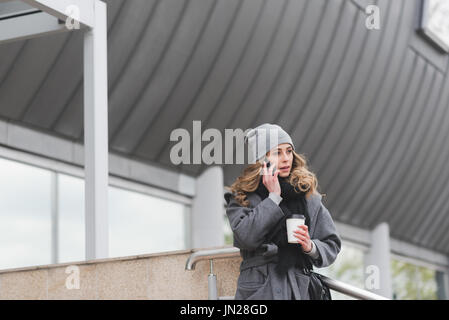Woman talking on phone while standing against building in city Stock Photo
