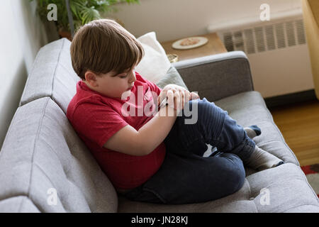 High angle view of boy using smart watch while sitting on sofa at home Stock Photo