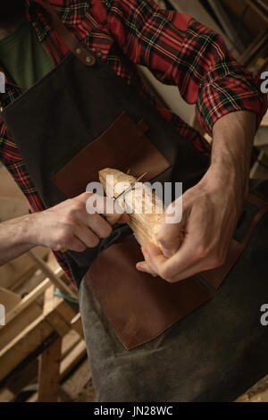Mid section of carpenter carving wood with chisel in workshop Stock Photo