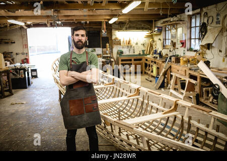 Portrait of confident carpenter standing with arms crossed in workshop Stock Photo