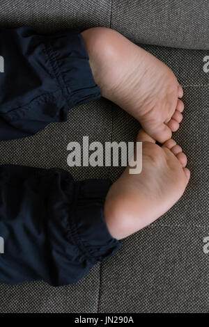 Low section of boy lying on sofa at home Stock Photo