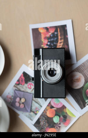 Overhead view of camera and photographs on table in cafe Stock Photo