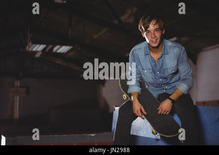 Portrait of man holding skateboard Stock Photo