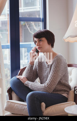 Young woman talking on mobile phone at home Stock Photo