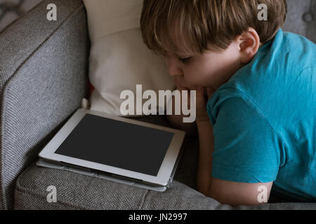 Close up of boy using digital tablet on sofa at home Stock Photo