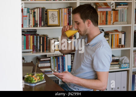 Man having juice while using mobile phone at table Stock Photo