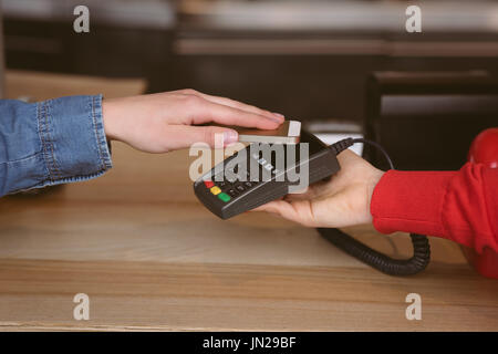 Close-up of woman paying bill through smartphone using NFC technology in cafe Stock Photo