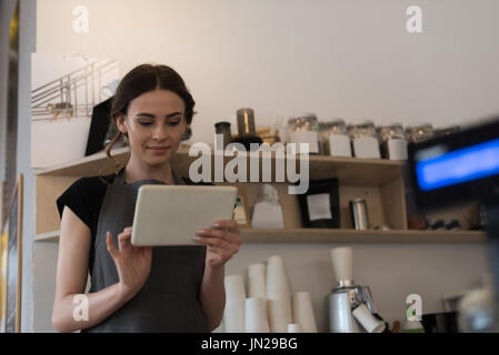 Female owner using digital tablet while standing in kitchen at cafe Stock Photo