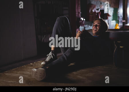 Smiling man using mobile phone in skateboard arena Stock Photo