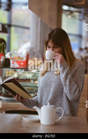 Beautiful woman reading book while having coffee in the cafe Stock Photo