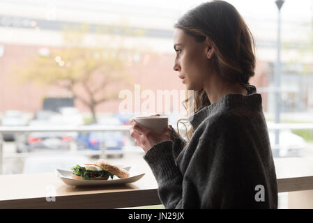 Side view of thoughtful woman having coffee in cafe Stock Photo